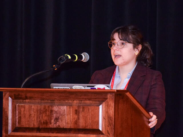 Katie Conner speaks at a podium welcoming everyone to the 2024 Hayes Forum.